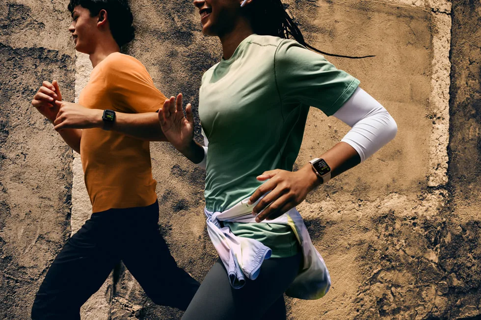 Apple Watch SE 3 takmış, yan yana koşan iki kişinin görseli.